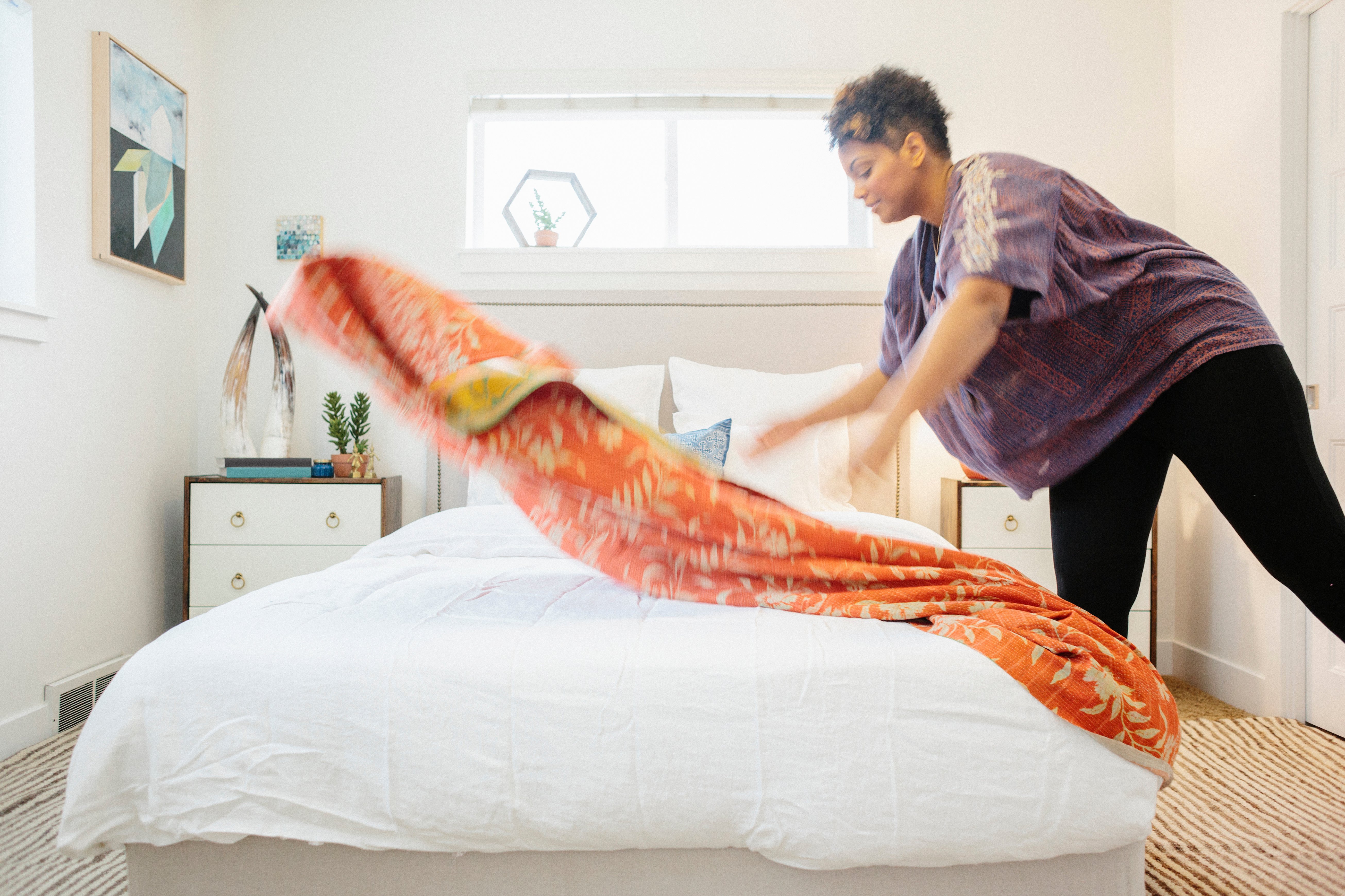 a-woman-spreading-a-floral-patterned-quilt-across-2023-11-27-04-53-29-utc